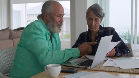 pareja madura usando una computadora portátil en casa