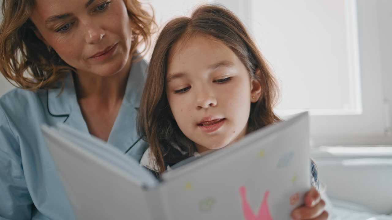 Mom kid enjoying novel spending free time at home closeup. Little girl reading