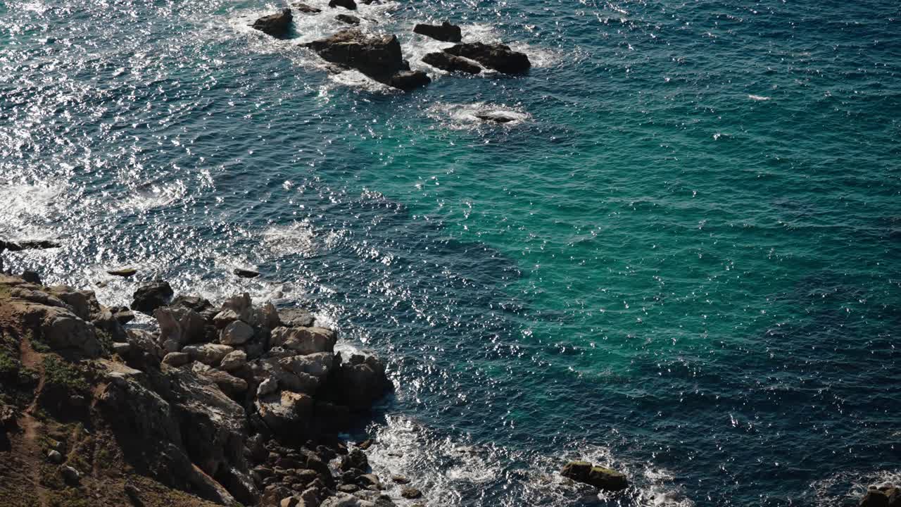 Waves sparkle under sunlight as they crash on rocky Atlantic coast in Tangier, Morocco