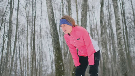 eine junge frau, die morgens im winterwald joggte, war müde und blieb stehen, um zu atem zu kommen. er kam wieder zu kräften, überwand die müdigkeit und lief weiter. ausdauer und überwindung von schwächen. vorstoßen