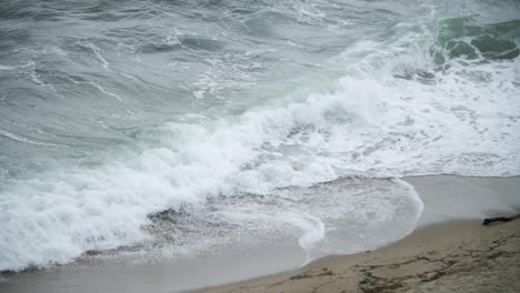 Turbulent-sea-waves-causing-foam-with-a-black-bird-flying-across-in-the-foreground