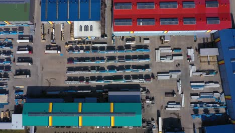 aerial view of a semi trucks with cargo trailers standing on warehouses ramps for loading unloading goods on the big logistics park with loading hub