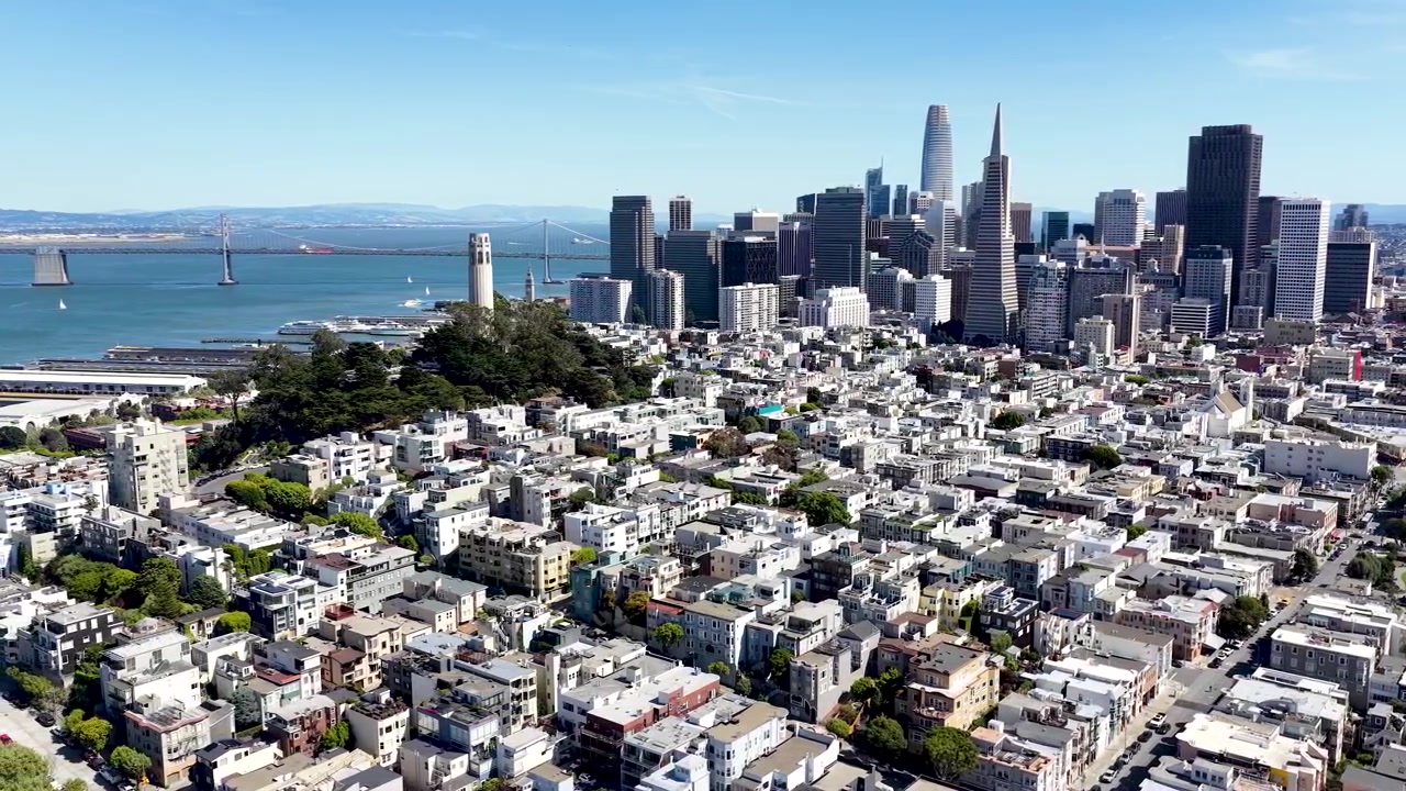 Droneopptak over rekkehusene på Telegraph Hill med skyskrapere i sentrum av San Francisco som reiser seg i det fjerne.
