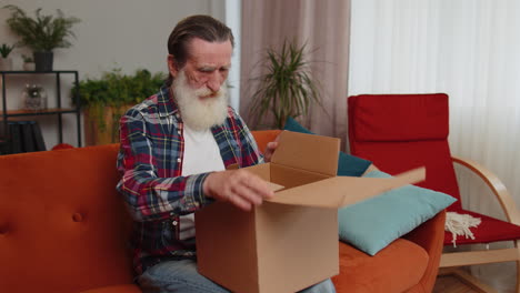 wütender unzufriedener käufer älterer alter mann, der ein paket auspackt, sich verärgert, verwirrt, falsche lieferung