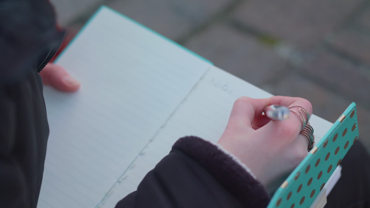 over the shulder shot of female student writing in notebook