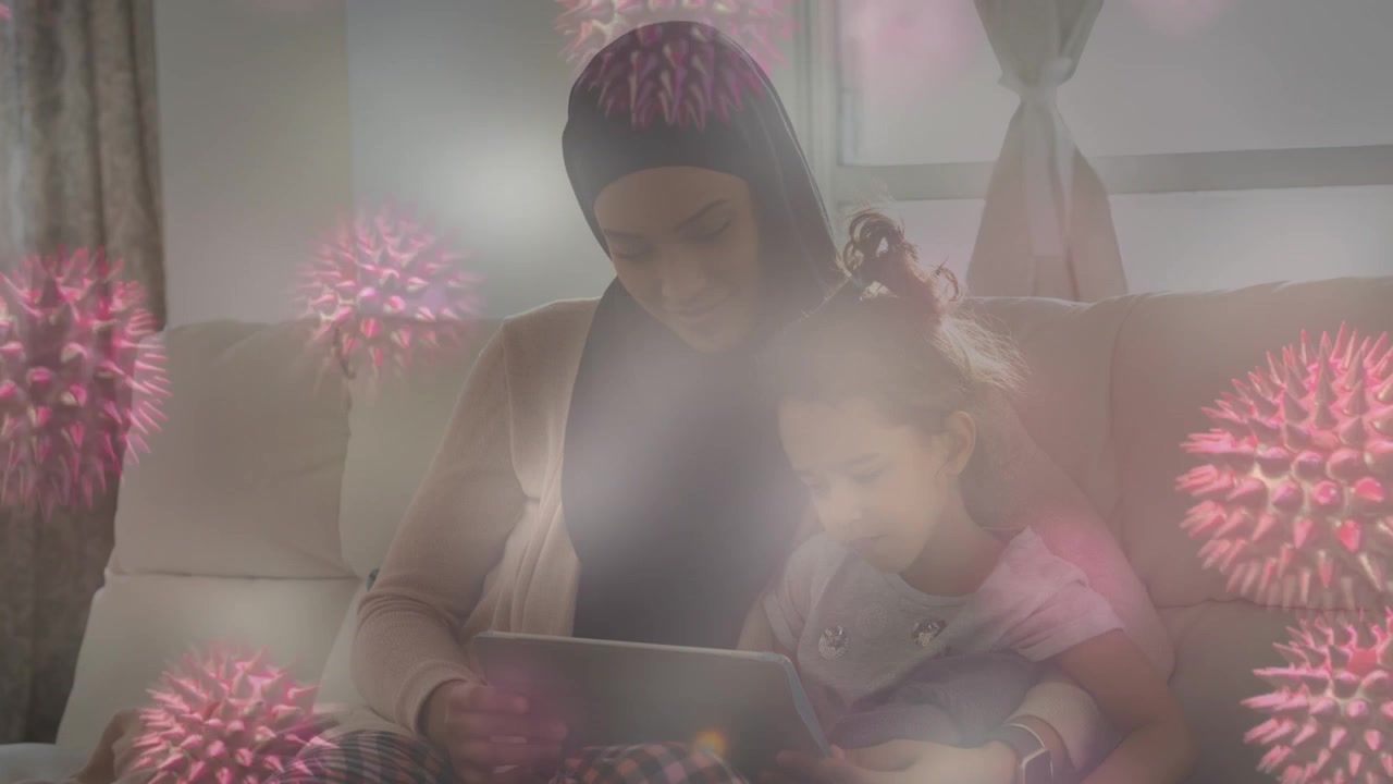 Composite video of covid-19 cells over woman in hijab and her daughter using digital tablet at home