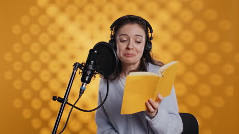 happy narrator wearing headphones reading aloud from book into mic