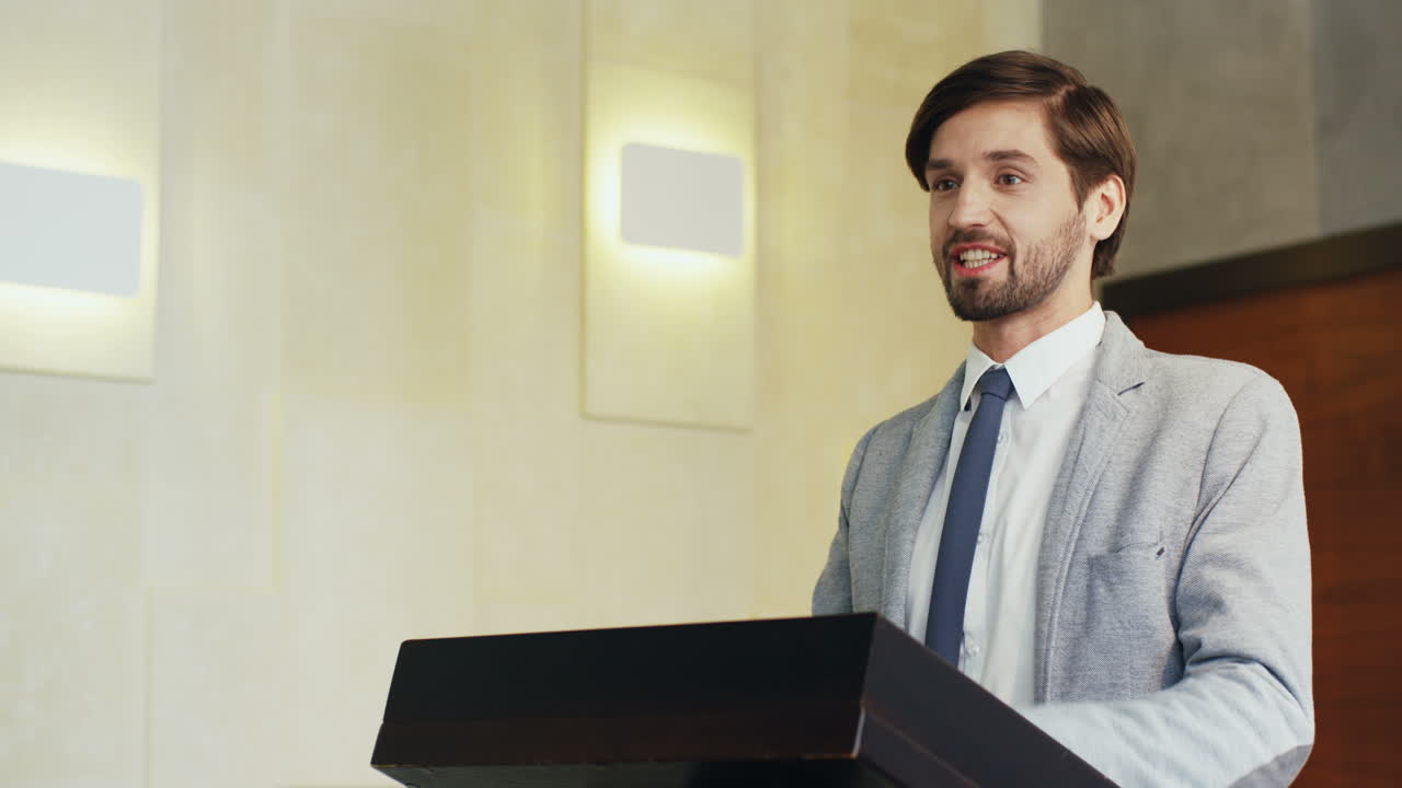 Close-up view of caucasian businessman speaker on a podium wearing formal clothes and talking in a conference room