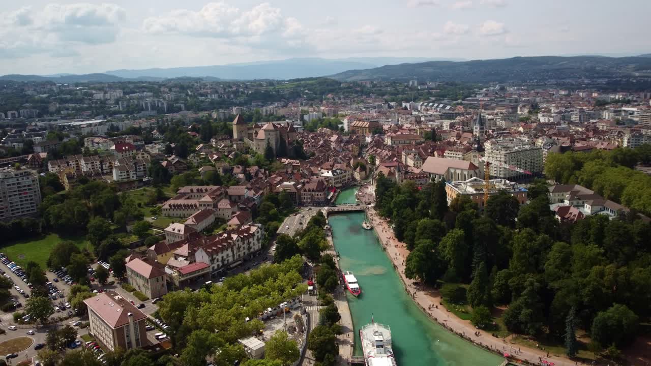 River Le Thiou running through the Annecy city centre. Ferries are moored up for tourist to visit the city. Footage rotates to the right on a beautiful sunny day