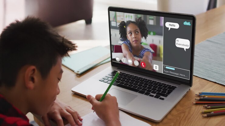 Ragazzo asiatico che fa i compiti e in videochiamata con un compagno di classe sul laptop a casa.