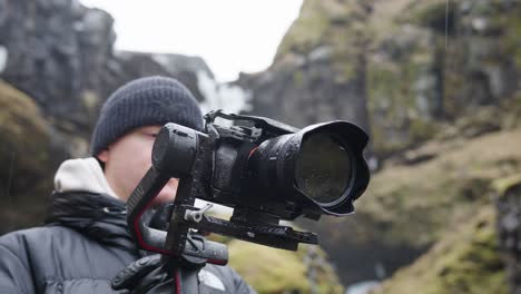 videógrafo masculino sostiene un gimbal electrónico con una cámara en el paisaje islandés