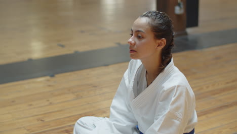 side view of karateka sitting on floor and drinking water