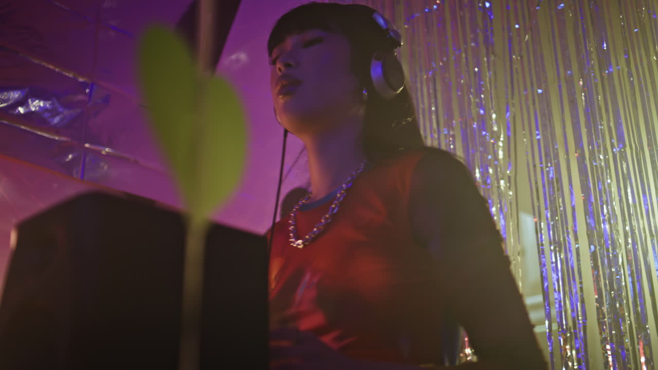 DJ playing music listening headphones in dimly lit nightclub closeup
