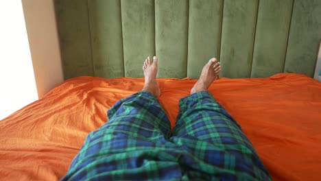 person lying in bed with plaid pajama pants