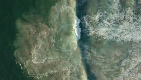 ocean waves breaking with white foam at llandudno beach, cape town, south africa - aerial top down