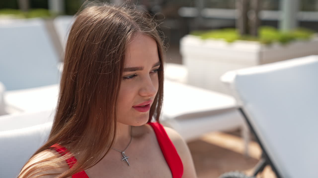 Beautiful young lady lies back in the white chaise lounge. Two relaxing friends having rest sunbathing during summer vacation.