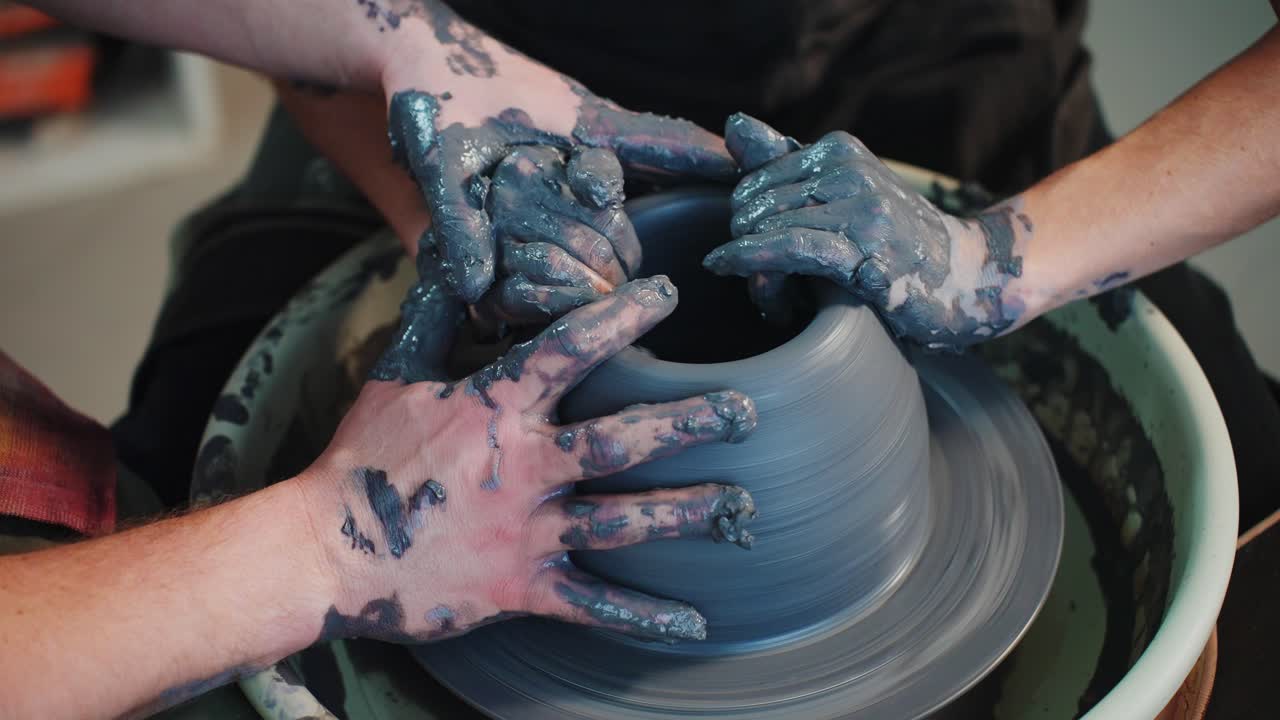 manos moldeando arcilla en una rueda de cerámica