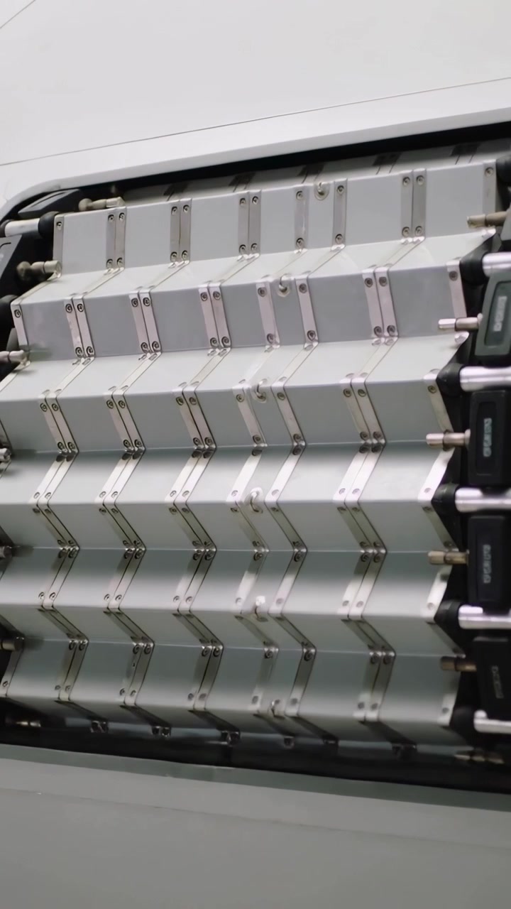 Vertical video: Sliding metal slats folding inward in machine bay, actuators driving cover closed