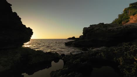 Toma-Deslizante-Cinematográfica-Hermosa-Playa-Rocosa-Al-Atardecer-En-La-Costa-De-Ibiza