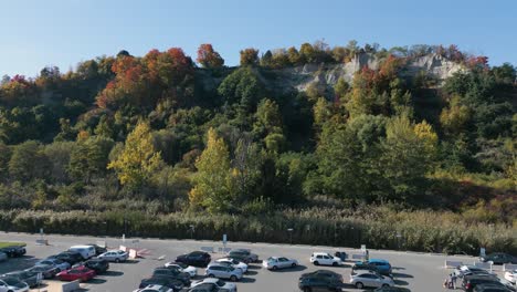 drone shot of a parking lot, we fly up to a hill filled with trees with fall colors