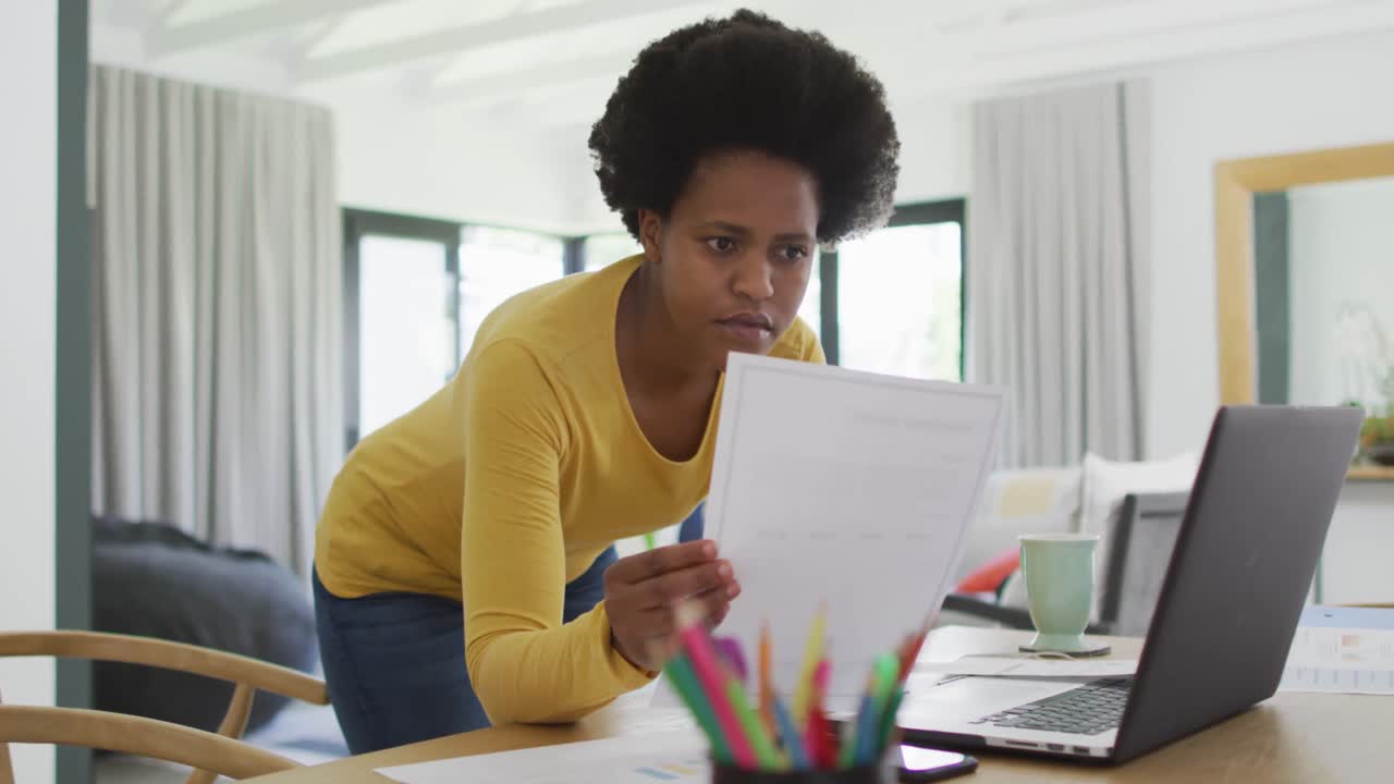 Felice donna afroamericana seduta al tavolo che usa il laptop