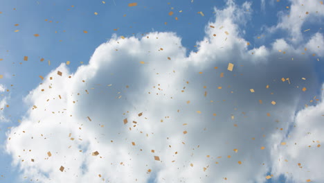 golden confetti falling against blue sky with white clouds