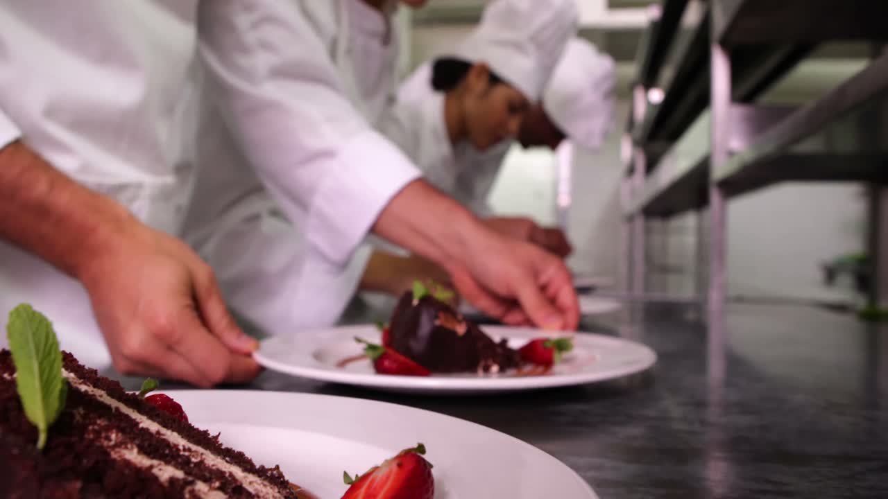 equipo de chefs adornando platos de postre con hojas de menta