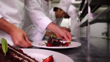 team of chefs garnishing dessert plates with mint leaves