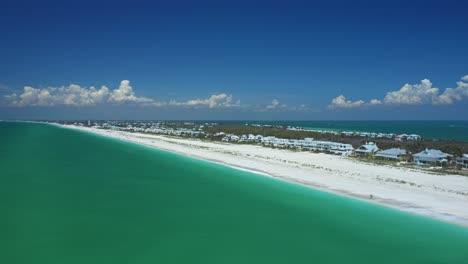 Aerial view of Gasparilla Island's white sand beach curving along emerald waters, with coastal homes under a clear blue sky in southwest Florida.