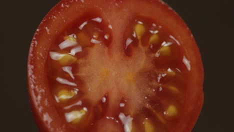 rotate of the halves of fresh ripe cut tomato on a dark background