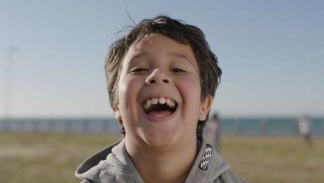 portrait of hispanic boy laughing cheerful at camera playing enjoying sunny seaside park