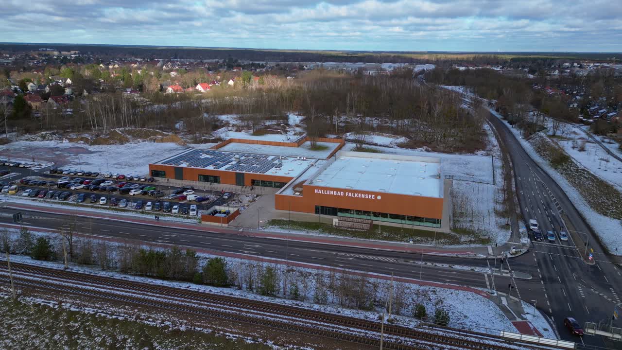 Indoor swimming pool with solar panels surrounded by snow and suburban homes in Falkensee Germany. Great aerial view flight static tripod hovering drone