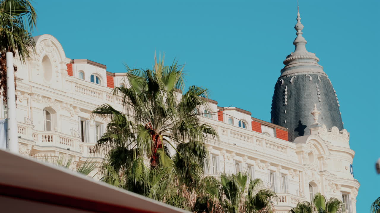 Beautiful facade of a historic luxury hotel framed by palm trees against a clear blue sky