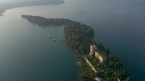 Close-up-aerial-shot-of-Isola-del-Garda,-the-harbor-with-small-yachts-and-neogothic-villa