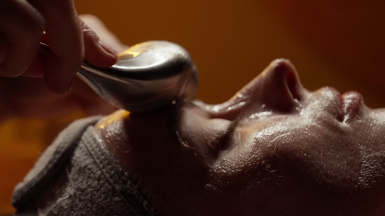 Nærbillede af kvinde, der får afslappende ansigtsmassage med metalredskaber