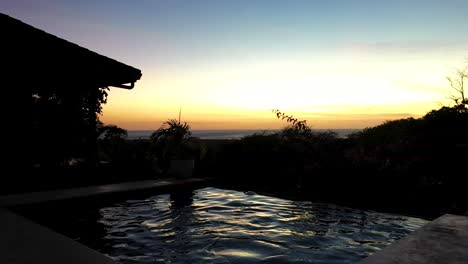 Mujer-Nadando-En-Una-Piscina-Infinita-Al-Atardecer-Con-Hermosas-Vistas