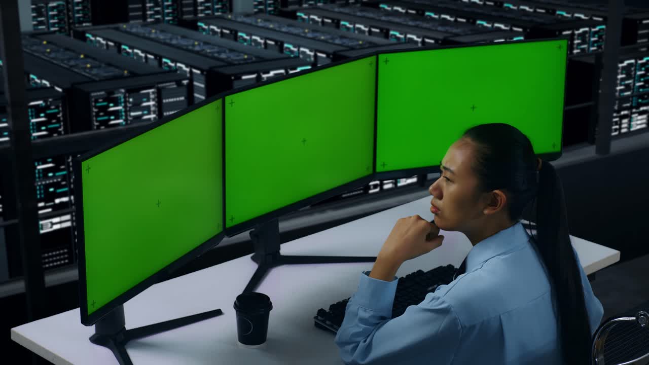 vista laterale di una donna asiatica che pensa a qualcosa e poi alza il dito indice mentre lavora con un monitor multi-computer in un centro dati