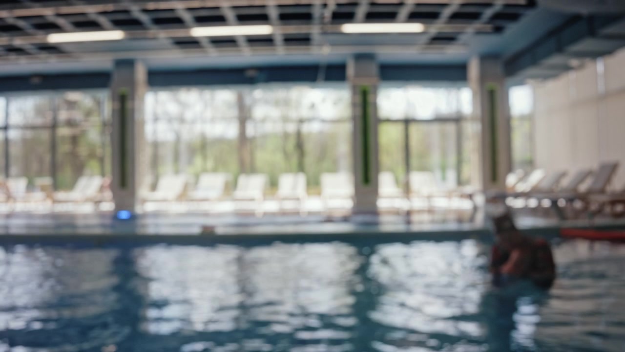 Blurred view of children swimming assisted by instructors during swimming lessons