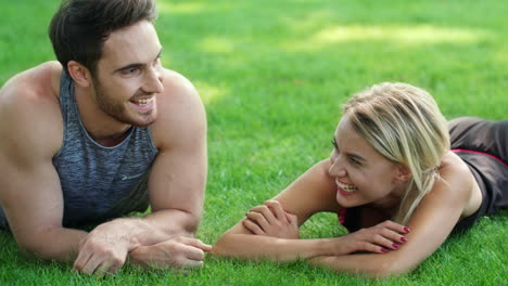 laughing man and woman flirting in park. sport couple lying on green grass