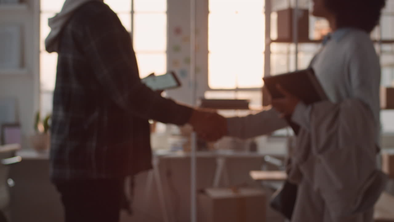 giovane uomo d'affari asiatico che lavora fino a tardi sviluppatore di software che incontra un cliente che stringe la mano che collabora con uno stagista per progettare un'applicazione mobile in ufficio al tramonto