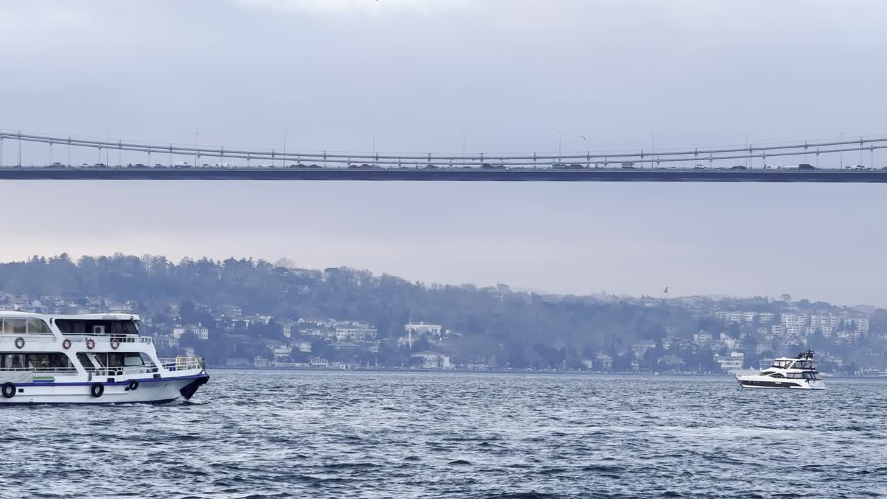 A passenger ferry with passengers in the Bosphorus. in the background you can see vehicles crossing the Bosphorus Bridge from the European continent to the Asian continent