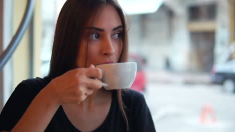 close up view of attractive young woman dreaming with cup of hot coffee sitting by the window in the coffee shot. break after