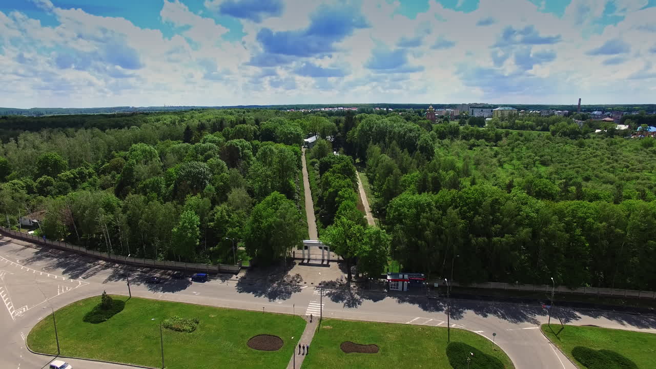 Large roundabout in the city near the green park. Two paths in the garden leading to the museum in the middle.
