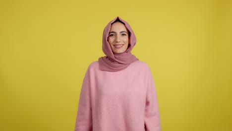 joyful woman in pink hijab celebrating with confetti on yellow background