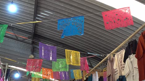 disparo de panorámica lenta de la fiesta mexicana papel picado guirnalda colgada en un mercado