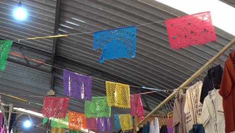 slow panning shot of mexican fiesta papel picado garland hanging in a market