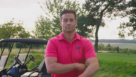 portrait of smiling male golfer standing by buggy on golf course