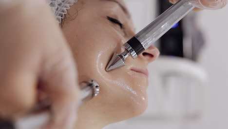 middleaged woman receiving micro currents facial cheek skin treatment from beautician in spa salon