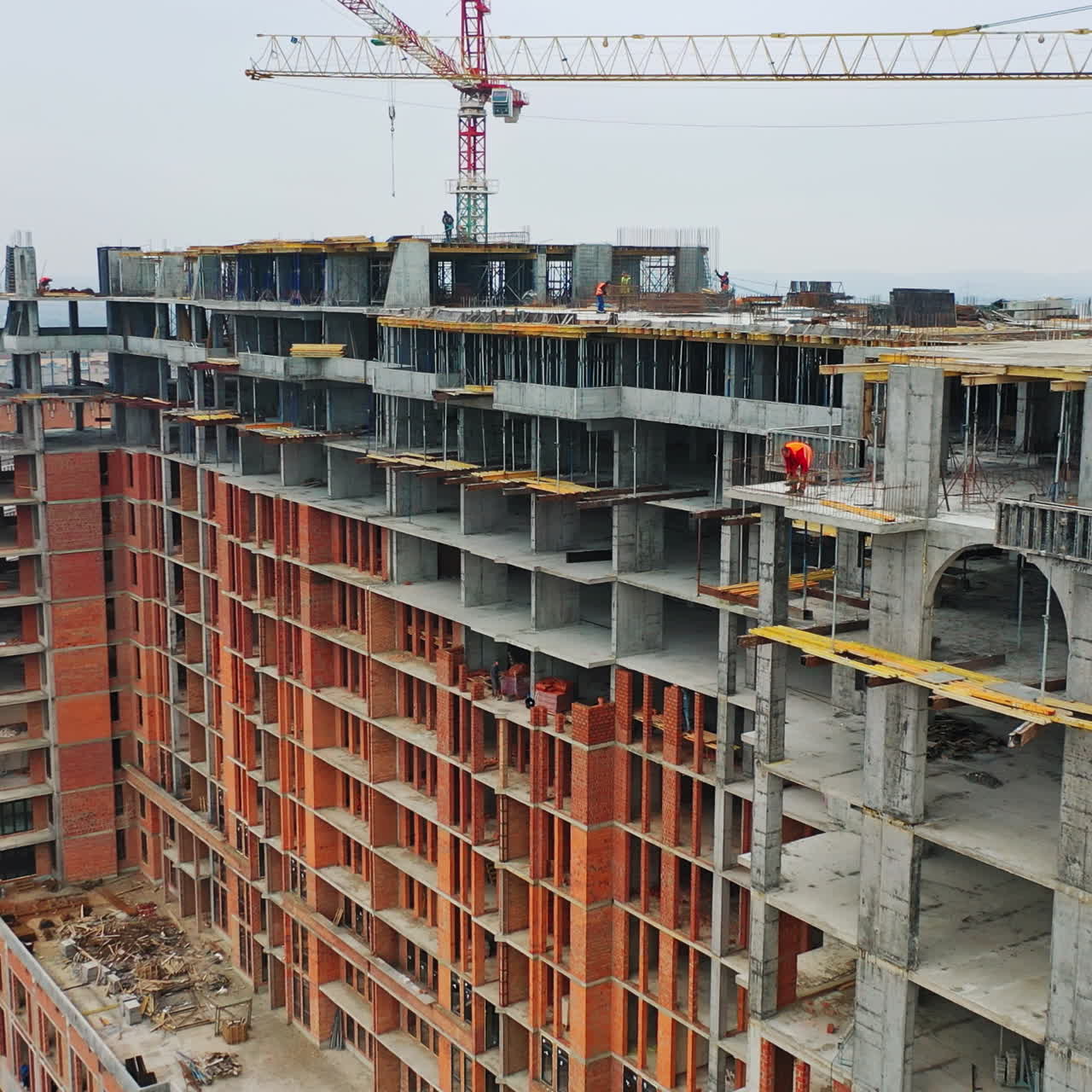 Construction site of modern skyscraper. Aerial side view on a new high-rise building in a new residential complex of a megacity.