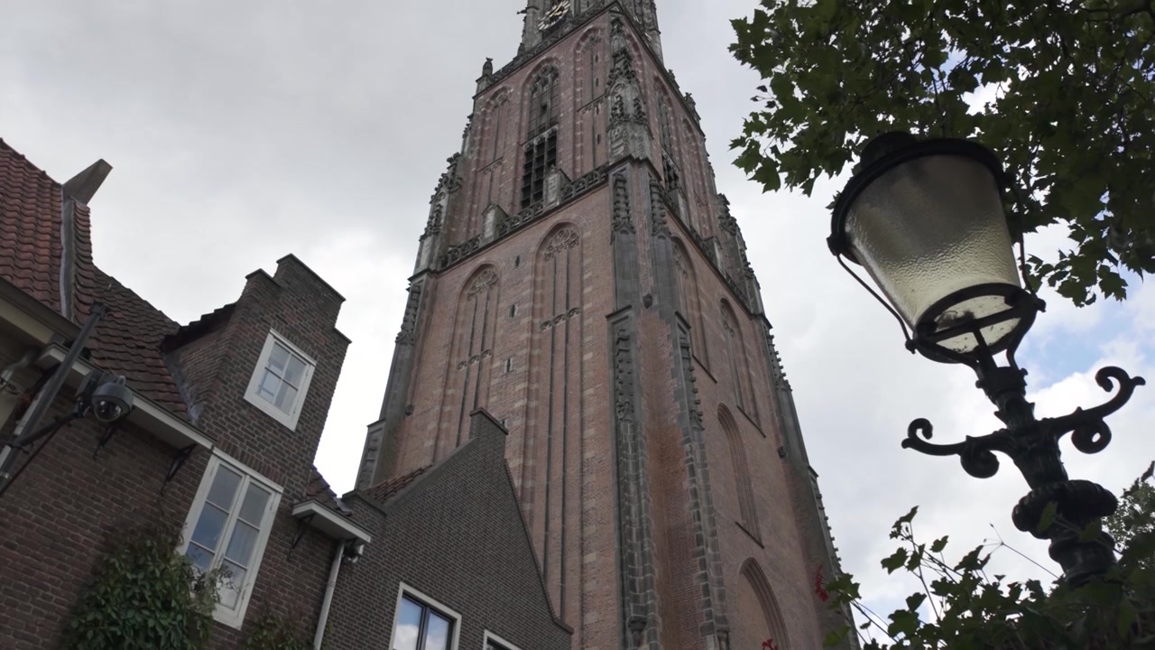 Onze Lieve Vrouwetoren i Amersfoort rager over historiske nederlandske hus og blomstrende slyngplanter